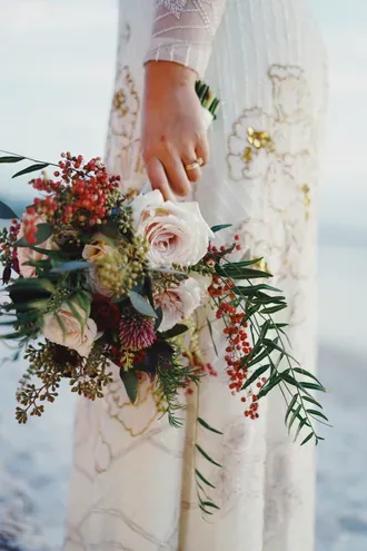 Novia sosteniendo un ramo de rosas y flores silvestres